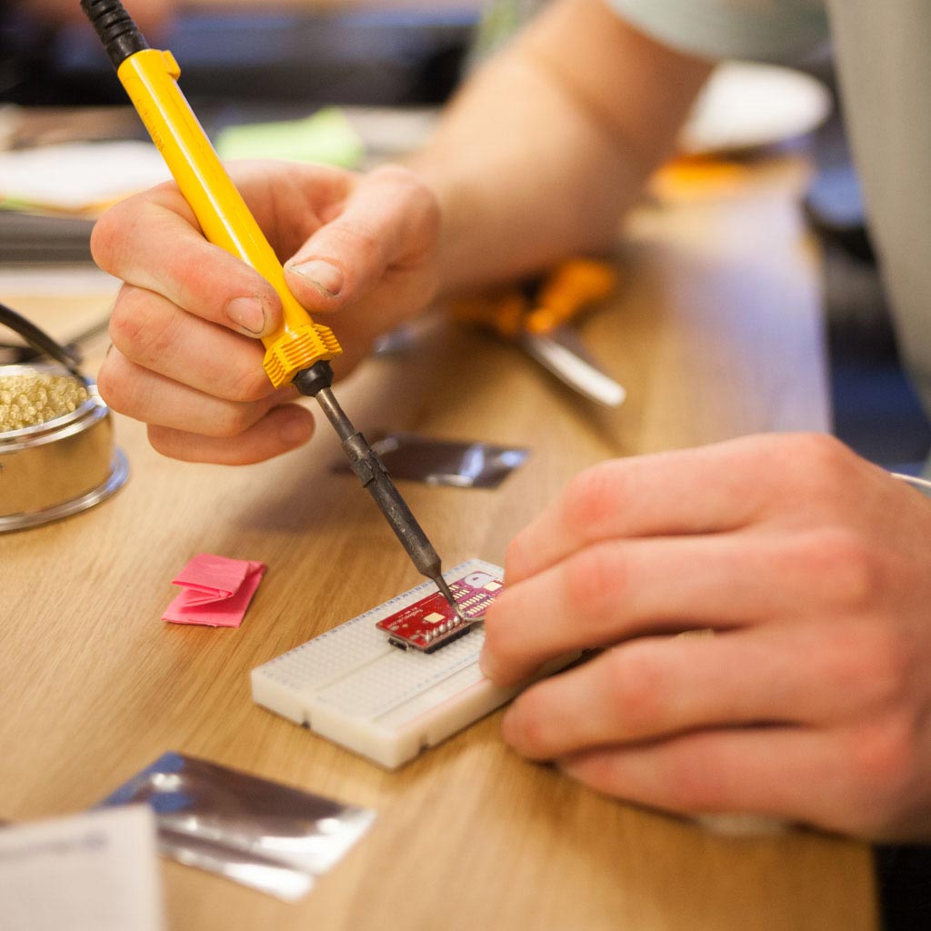 Photo of an IDEO designer soldering a circuitboard during an IDEO mobility project