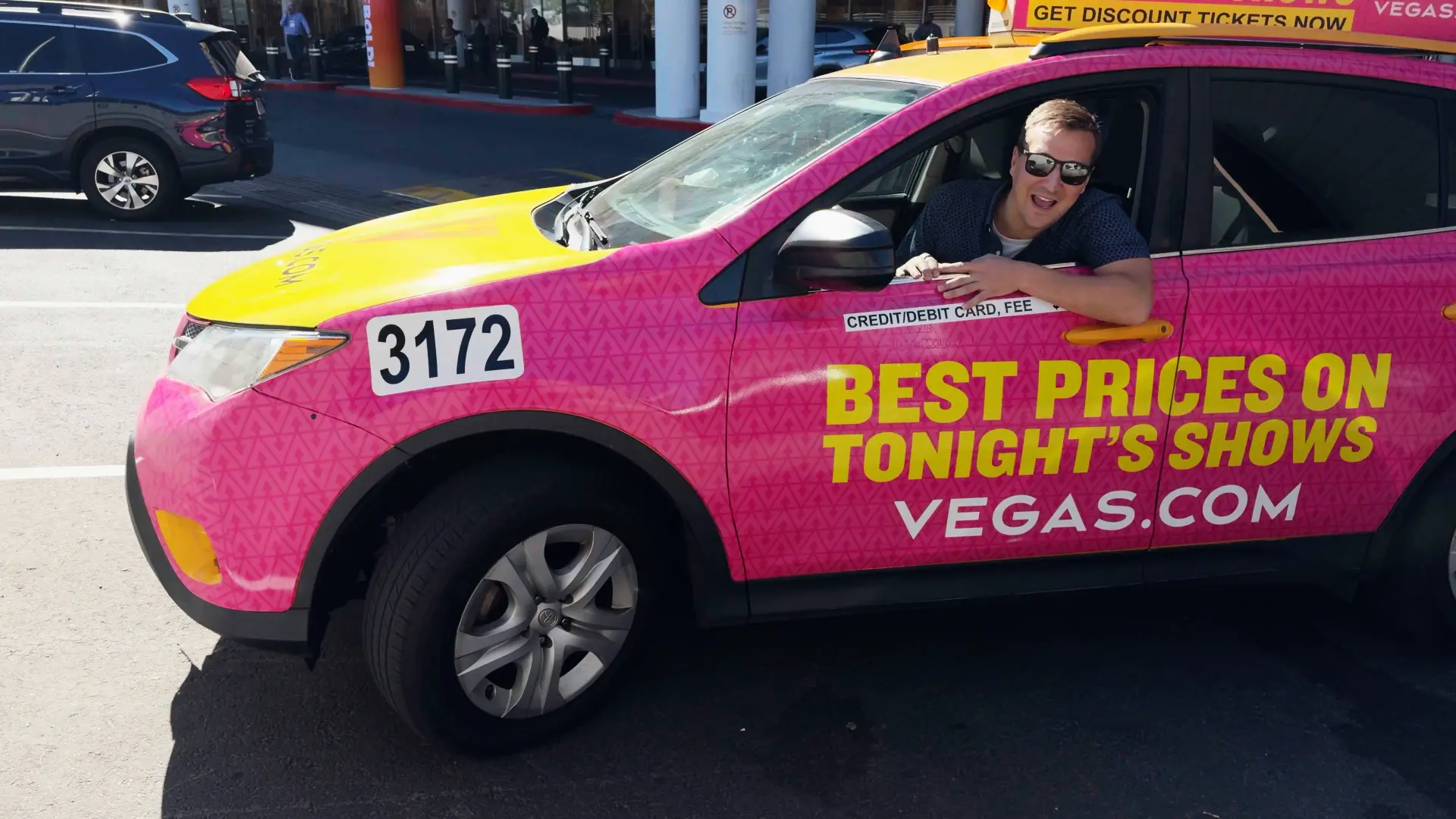 Nate Tower driving a hot-pink taxi cab in Las Vegas